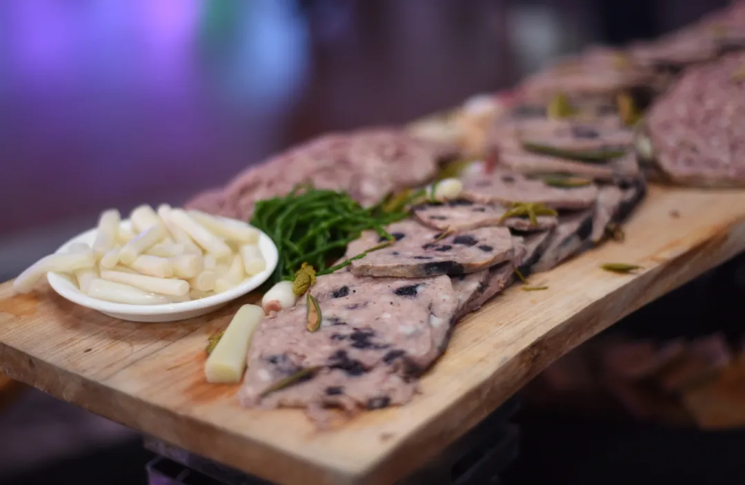 A wooden platter featuring Arctic cuisine, including sliced meats and vegetables.