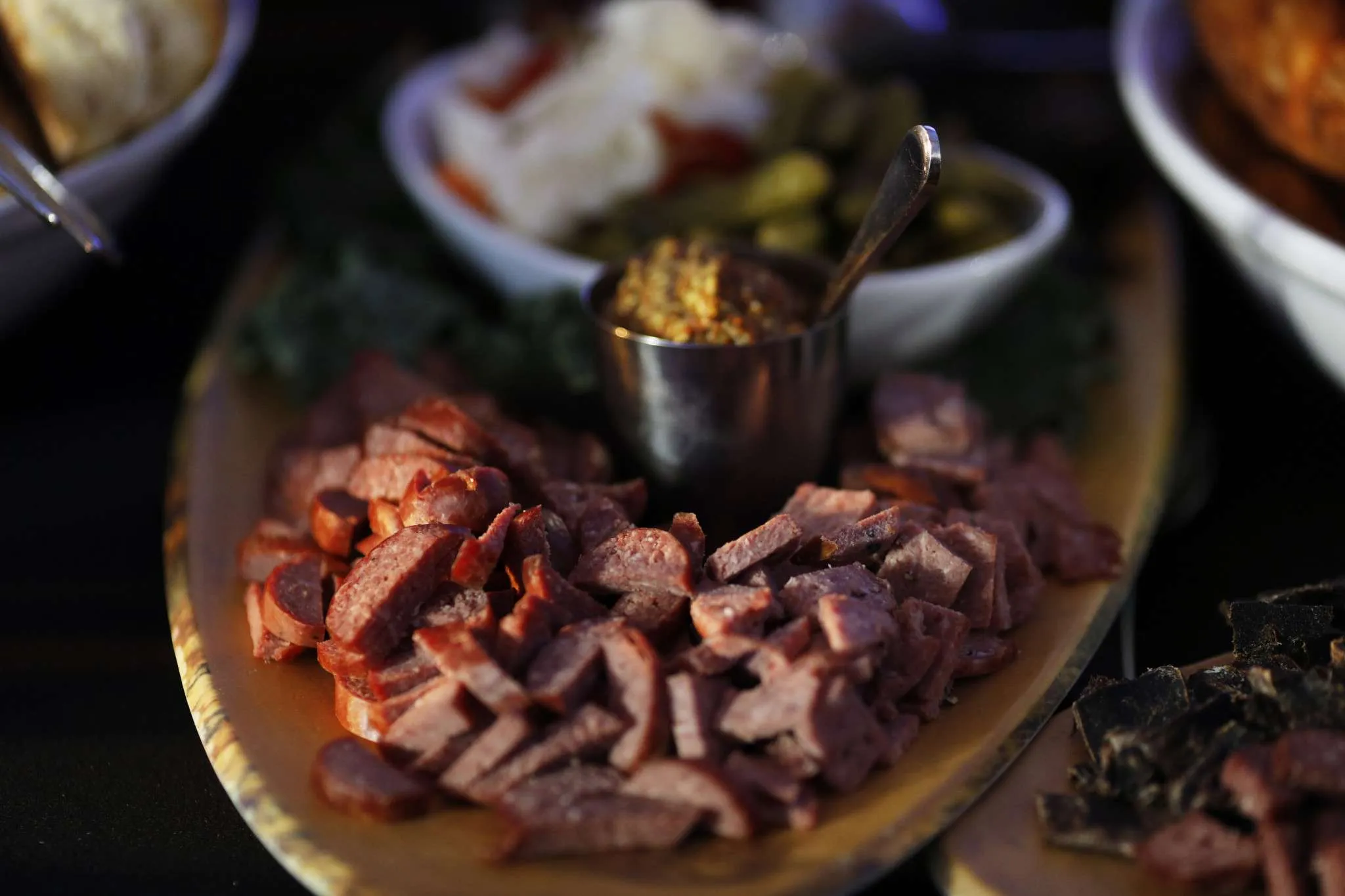 Platter of sliced cured meats served with condiments and pickled vegetables