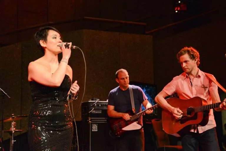 A musical performance with a vocalist and guitarists on stage during an Inuit cultural event